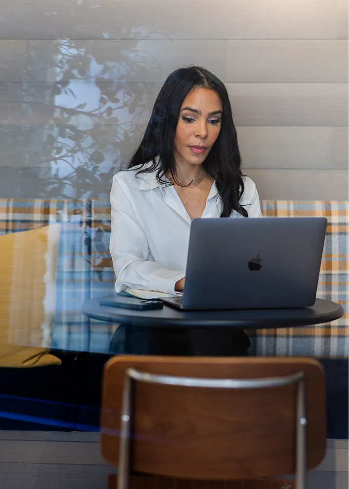 A professional sitting at a cafe table, working on a laptop